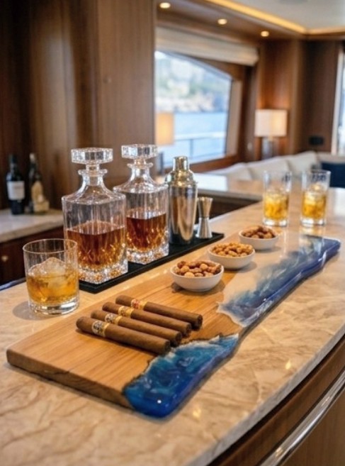 Lunasea live-edge cherry board with cobalt and seafoam resin wave on a yacht bar, laid with hand-rolled cigars beside crystal whisky decanters and tumblers
