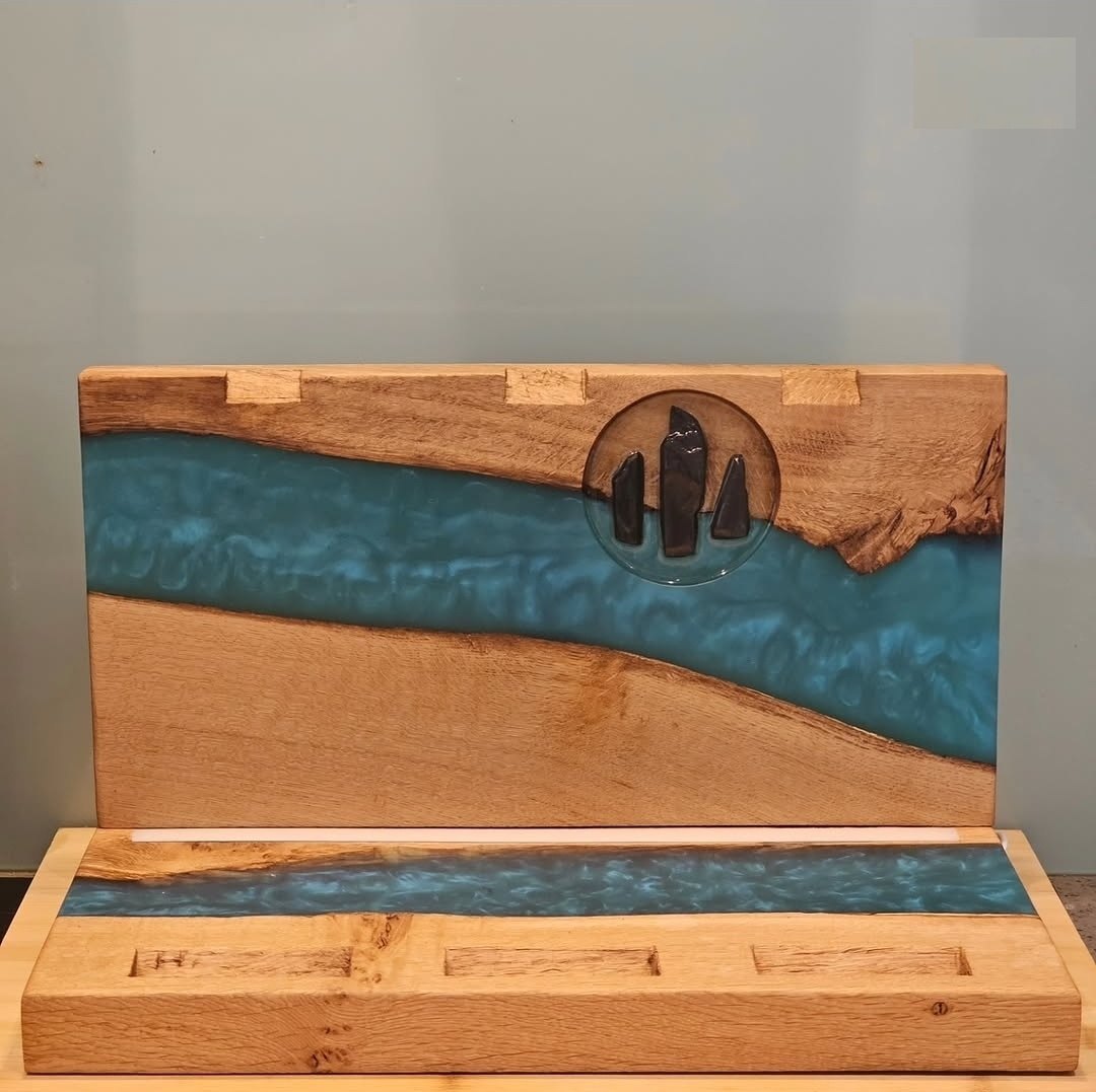 The Trio display assembled without bottles — oak backboard with teal resin river and slate standing-stone logo above the carved oak base